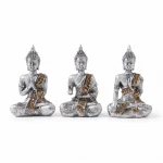 Candlelight side-by-side arrangement of three identical silver Buddha statues