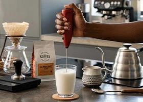 Handheld milk frother creating foam for latte at home in Kenya